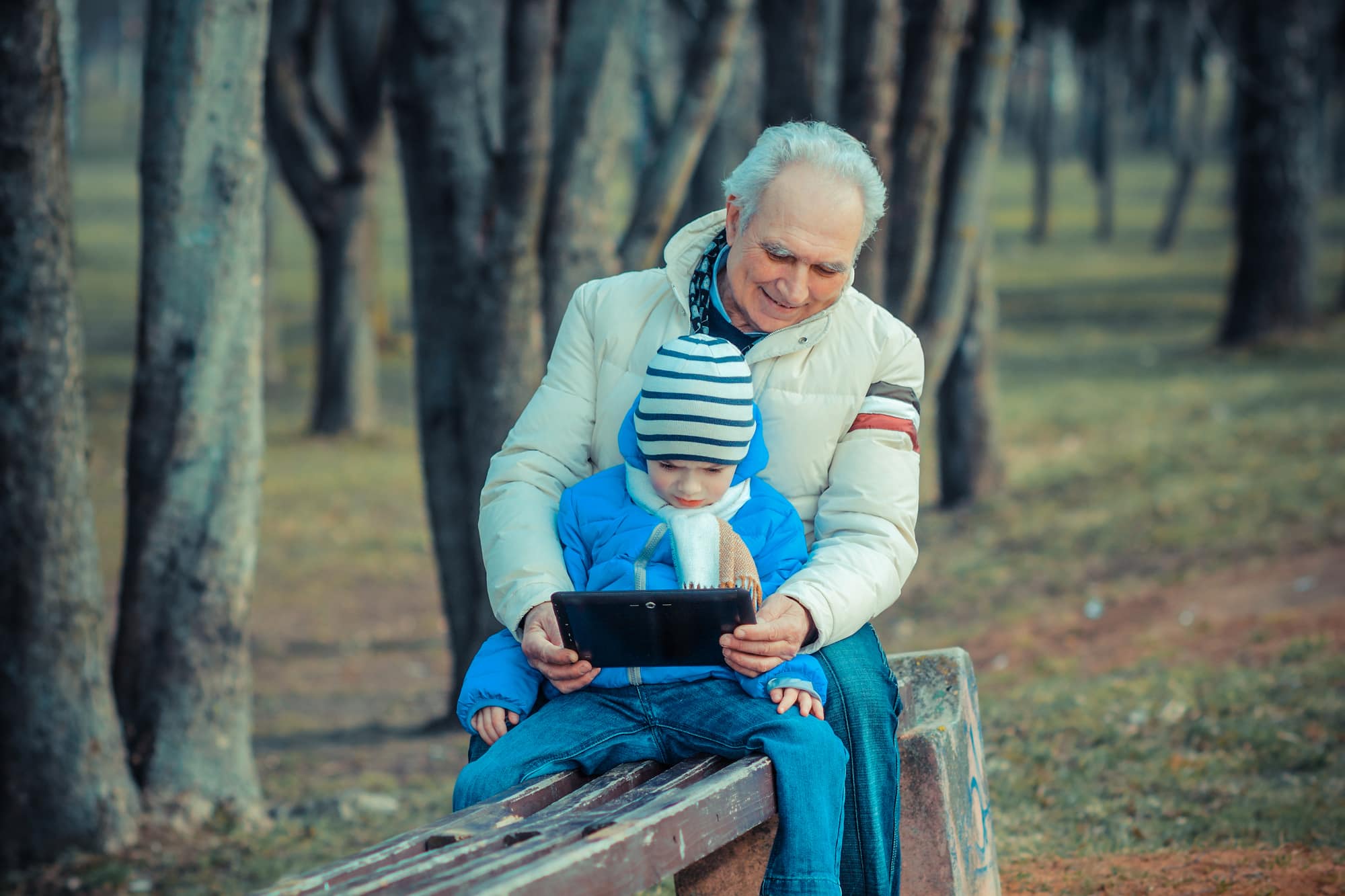older man using tabled technology with child